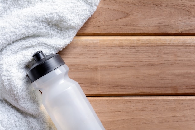 bovenaanzicht witte doek en plastic fles water op houten tafel