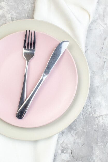 bovenaanzicht witte plaat met roze bord en bestek op lichte ondergrond keuken glas eten maaltijd horizontale kleur dames