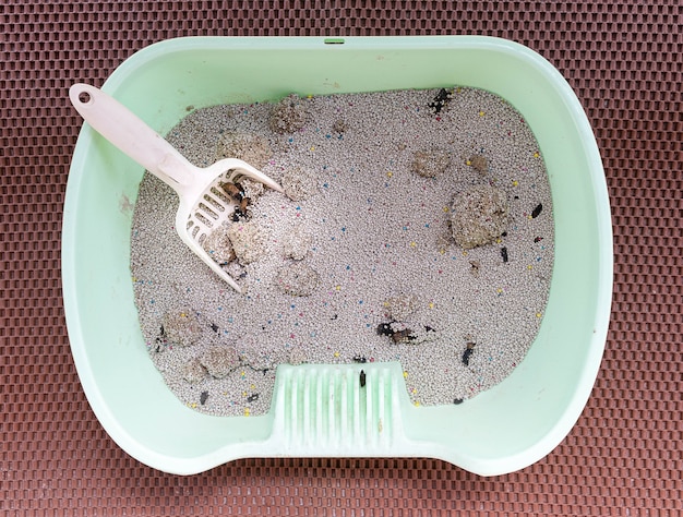 Bovenaanzicht witte schep in de kattenbak