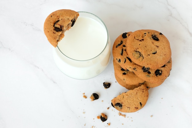 Bovenaanzicht zelfgemaakte chocoladeschilferkoekjes en glas melk op marmeren achtergrond