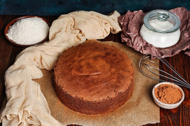 Bovenaanzicht zelfgemaakte ronde chocolade biscuit of chiffon cake met ingrediënten eieren meel melk op houten tafel zelfgemaakte bakkerij concept voor achtergrond en behang