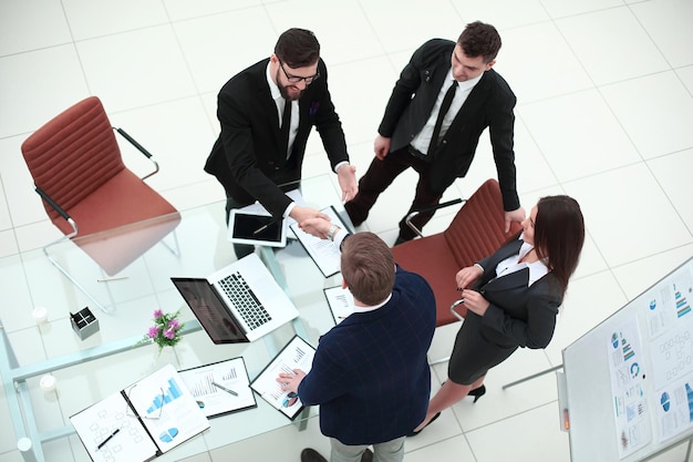 Bovenaanzichthanddrukken van zakenpartners op het bureau