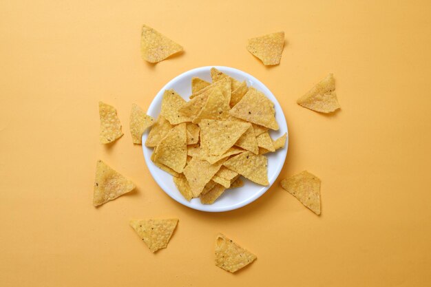 Bovenbeeld van corn nachos chips op een bord geïsoleerd op een gele achtergrond