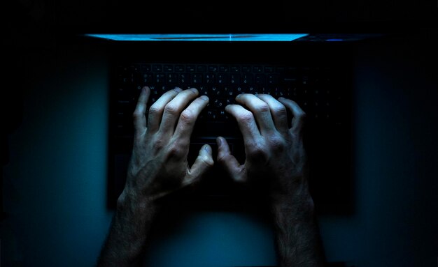 Bovenbeeld van de handen van een programmeur op zijn laptop
