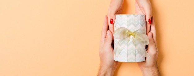 Foto bovenbeeld van een man en een vrouw die geschenken geven en ontvangen voor een feest op een kleurrijke achtergrond