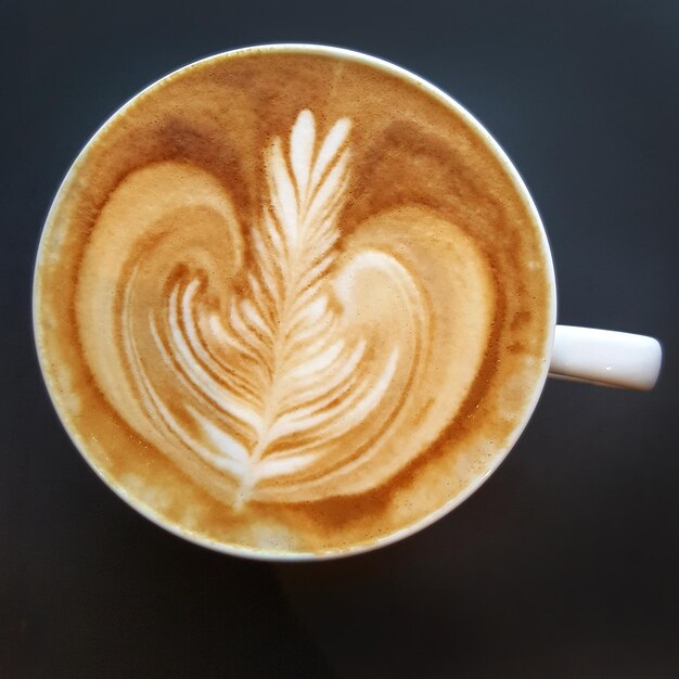 Bovenbeeld van een mok koffie met latte op zwarte achtergrond