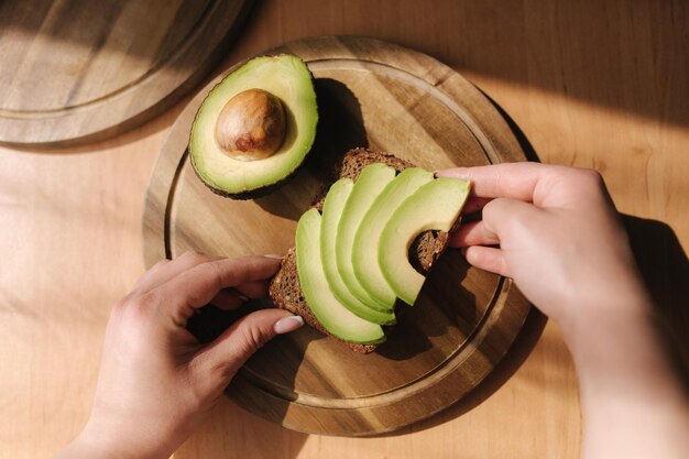 Bovenbeeld van gesneden avocado op donker brood op houten tafel Tweede helft van avocado met pit