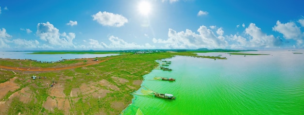 Bovenbeeld van het vissersdorp Ben Nom fris groen beeld van het groene algenseizoen op het meer Tri An met veel traditionele vissersboten verankerd in Dong Nai Vietnam