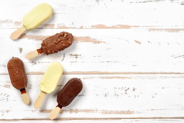 Foto bovenbeeld van ijsjes bedekt met chocolade op een witte houten achtergrond ruimte voor tekst