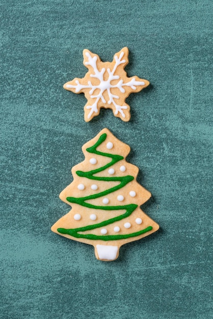 Foto bovenbeeld van kerstboom en sneeuwvlok cooikes met peperkoek man met masker op groene tafel achtergrond