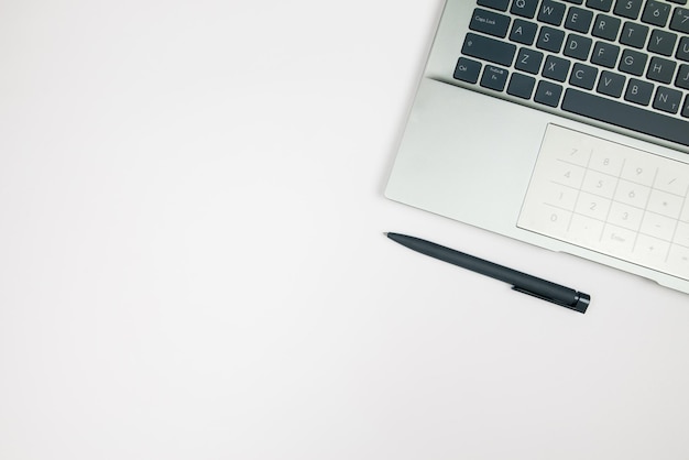 Bovenbeeld van laptop en pen op witte achtergrond