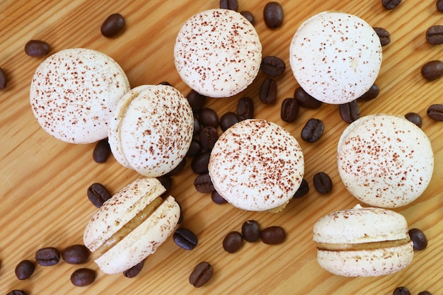 Bovenbeeld van Tiramisu-macarons met koffieboontjes verspreid over een houten achtergrond