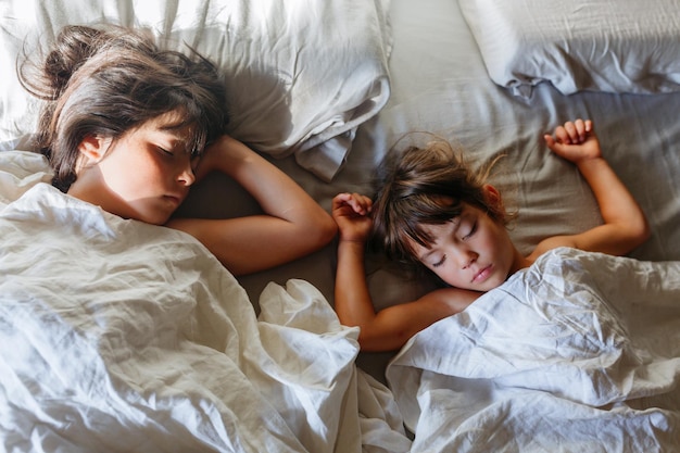 Bovenbeeld van twee kinderen die op het bed van hun ouders slapen