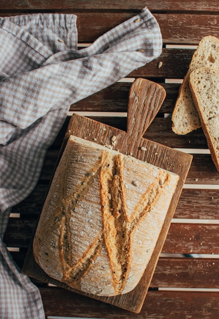 Bovenbeeld van vers gebakken brood op een rustieke houten snijplank en servet