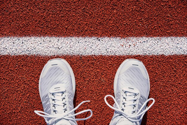 Foto bovenbeeld van witte mannelijke loopschoenen bij de startlijn op het stadion.