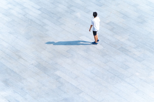 Bovenkant van luchtfoto van jongen die op voetgangerspad buiten loopt om te reizen of te sporten