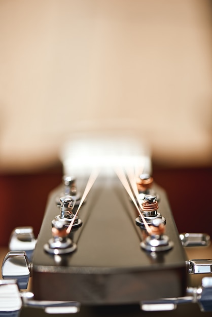 Bovenste deel van de gitaar. Verticale close-upfoto van gitaarmechanisme om gitaarsnaren te rijgen: stemsleutels, toestellen. Muziekinstrumenten. Muziekconcept.