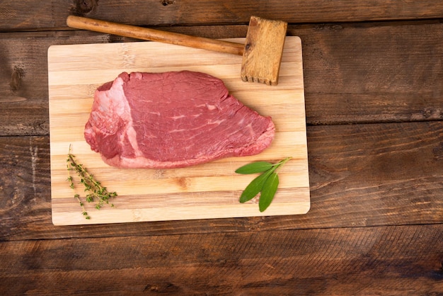 Bovenste steak op bamboe bord met salvia en rozemarijn op houten achtergrond