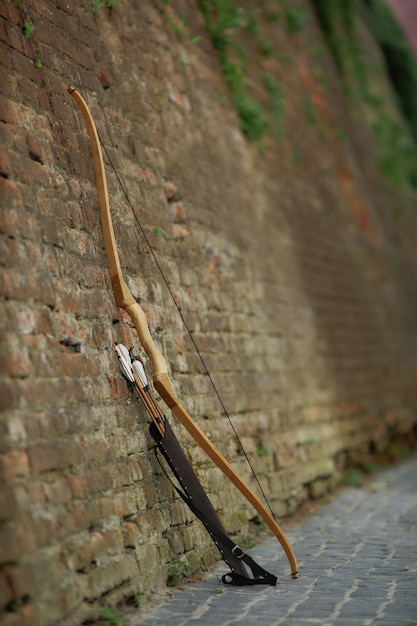 Photo bow and arrows leaning on brick wall in old town.