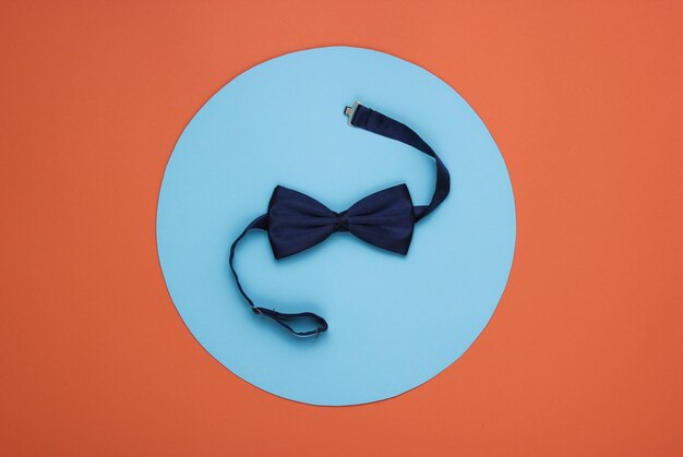 Bow tie on coral paper with blue circle in the middle.