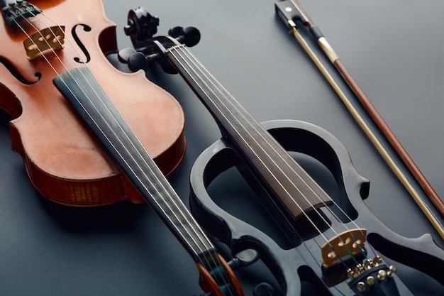 Bow, wooden retro violin and modern electric viola, closeup view, nobody. Two classical string musical instruments