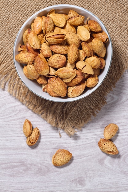 Bowl of almonds isolated on wood background 