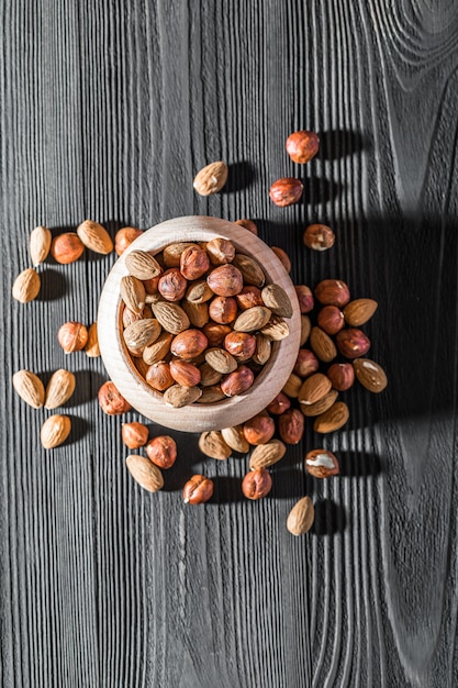 Bowl of almonds on wood textured background, top view, close-up