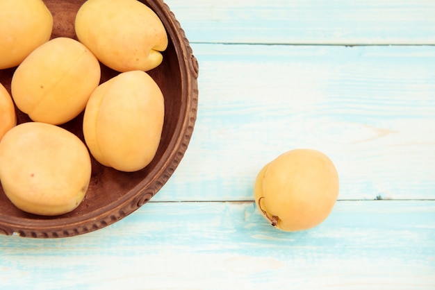 Bowl of apricots on wooden blue background