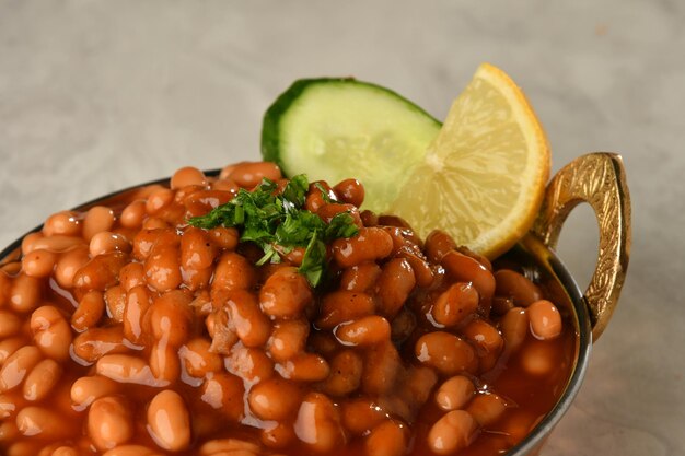 A bowl of baked beans with a slice of lemon on the side