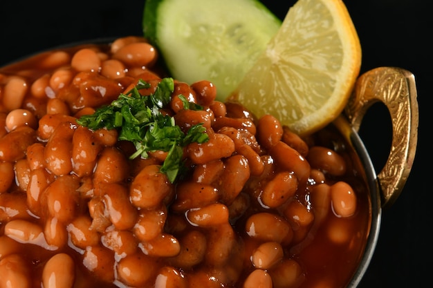 A bowl of baked beans with a slice of lime on the side