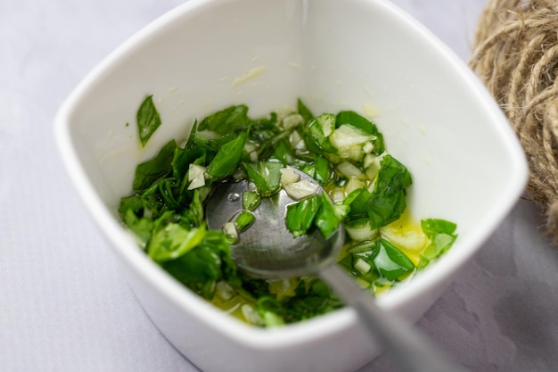 A bowl of basil and garlic sauce with a spoon in it.