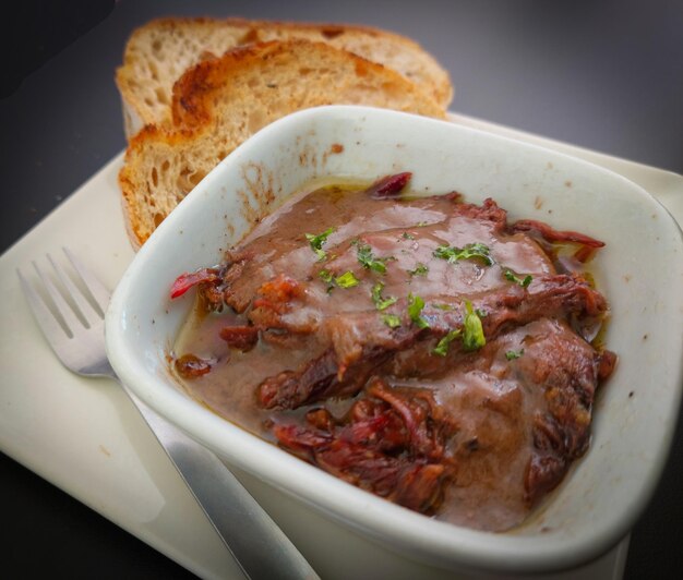 A bowl of beef stew with a fork on the side.