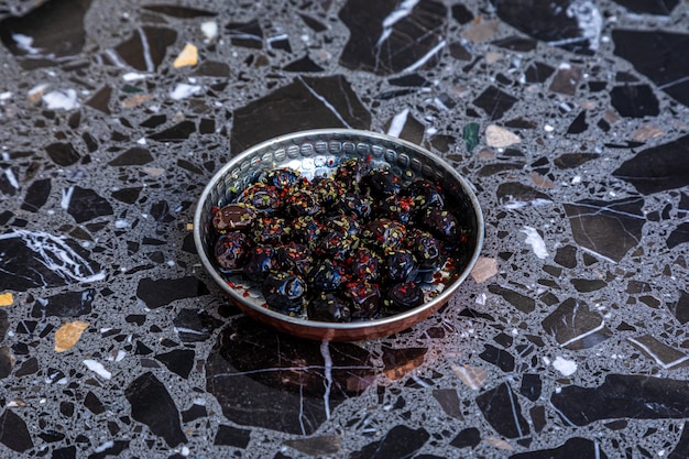 Photo a bowl of black olives with rainbow colored sprinkles on the rim.