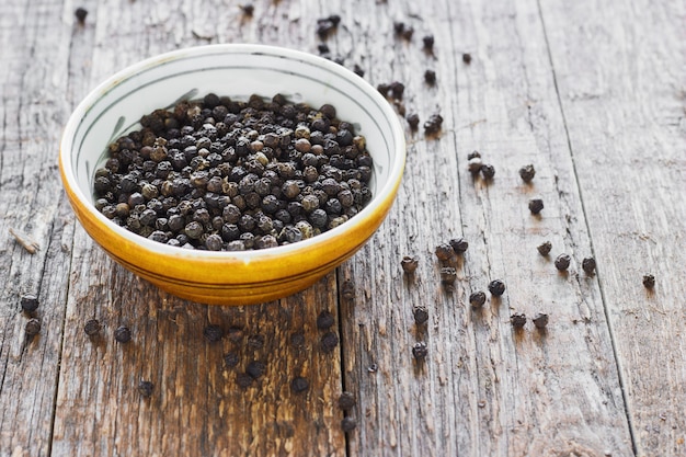 Bowl of black pepper on wooden table