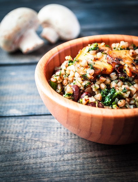 Foto ciotola di grano saraceno bollito con champignon fritto, spinaci e fagioli rossi