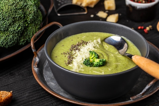 Bowl of broccoli cream soup with parmesan cheese and crunchy croutons on wooden table top view