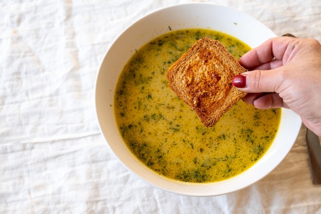 Foto una scodella di zuppa di broccoli con dentro un pezzo di pane immerso.