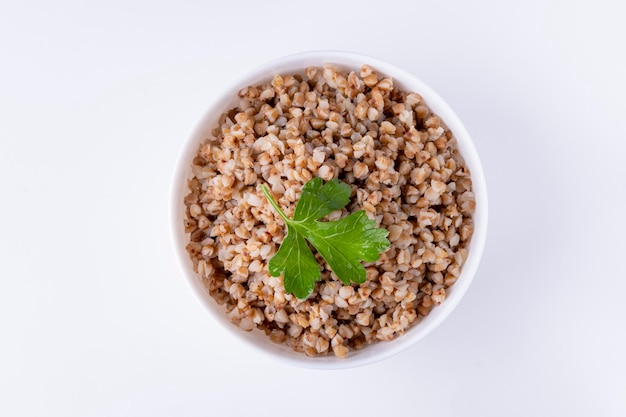 Bowl of buckwheat flakes isolated on white background, top view.