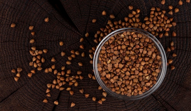 Ciotola di chicchi di grano saraceno su sfondo nero vista dall'alto