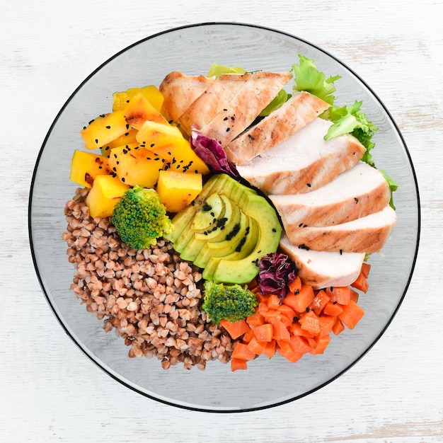 Bowl Buddha Buckwheat pumpkin chicken fillet avocado carrots On a white wooden background Top view Free space for your text