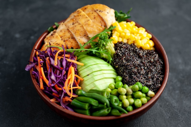 Bowl Buddha.Quinoa, chicken breast, avocado, red cabbage, arugula, carrot, green peas, corn, broccoli, green beans in a plate