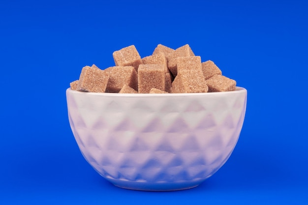 Bowl of cane sugar on a blue background top view