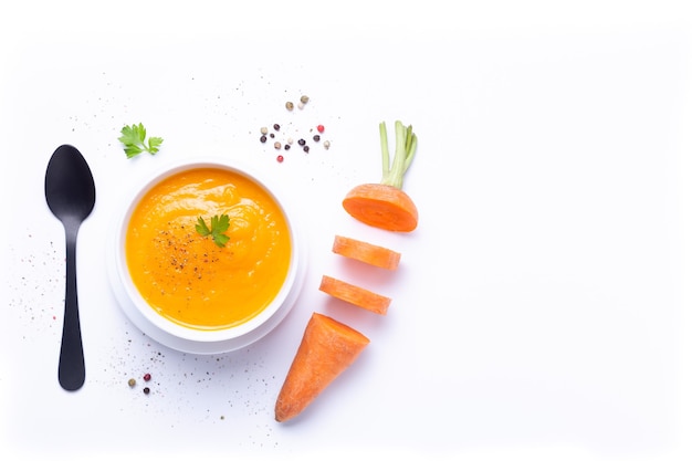 Photo bowl of carrot soup  with carrot pieces isolated on white background