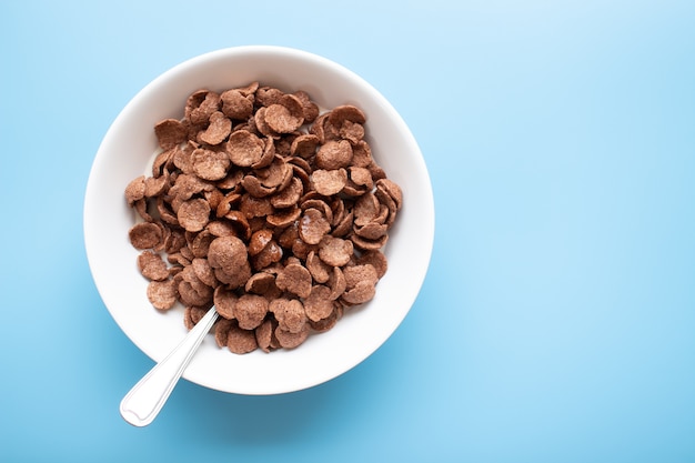 Bowl of cereal chocolate flavor and milk with silver spoon. Breakfast top view