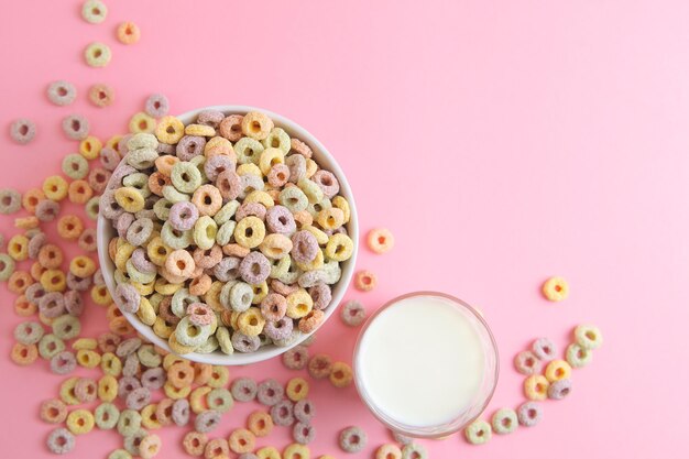 Photo bowl of cereal with a glass of milk on a pink background