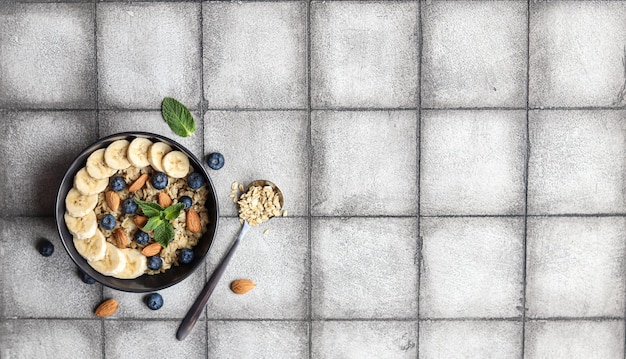 A bowl of cereal with nuts and berries on a gray tile background.