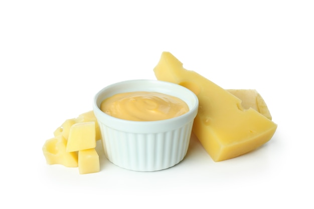 白い背景で隔離のチーズソースとチーズのボウル