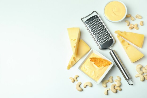 Bowl of cheese sauce and ingredients on white background