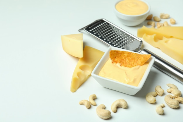 Bowl of cheese sauce and ingredients on white background