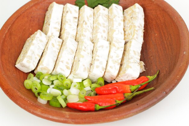 A bowl of cheese with green onions and red peppers.